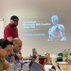 Le CEO d’un centre de formation professionnelle à Tunis présente Microsoft 365 Copilot lors d’une session de formation, tandis que deux participants suivent attentivement la démonstration sur leurs ordinateurs portables.